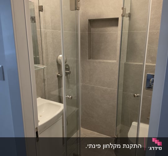 מקלחת עם דלתות זכוכית ושירותים
